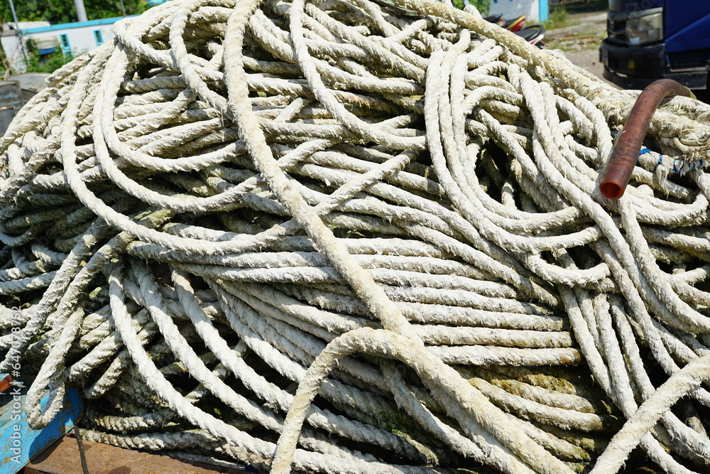pile of white big boat ropes in the harbor at noon