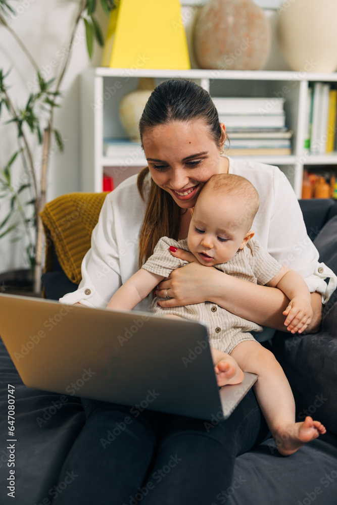 Happy mother using laptop while holding her baby close to her. Happy mother using laptop while holding her baby close to her.