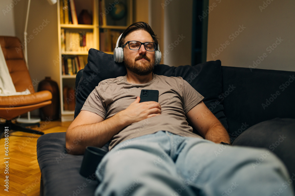 Caucasian man fell asleep while listening to relaxing music in the evening.