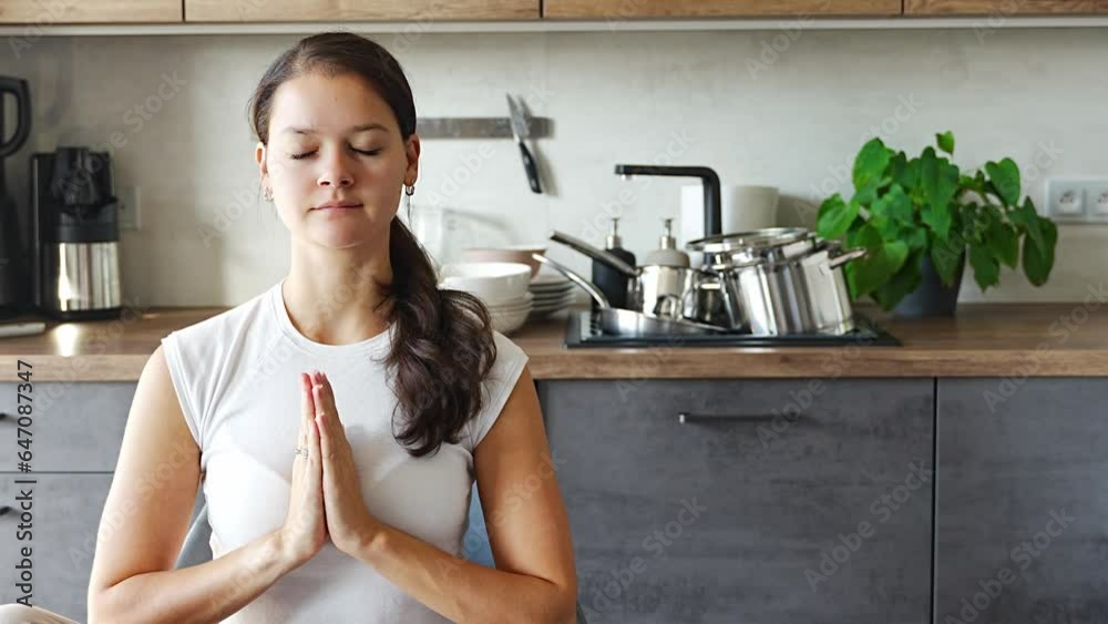 Young woman is sitting and doing meditation on background of dirty dishes in the kitchen. Slowdown, self-care, slow life concept Young woman is sitting and doing meditation on background of dirty dishes in the kitchen. Slowdown, self-care, slow life concept