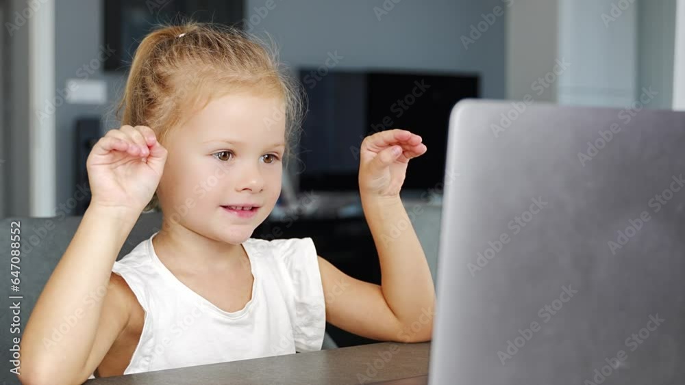 Little girl does finger gymnastics online on the laptop home. Distance learning concept. Little girl does finger gymnastics online on the laptop home. Distance learning concept.
