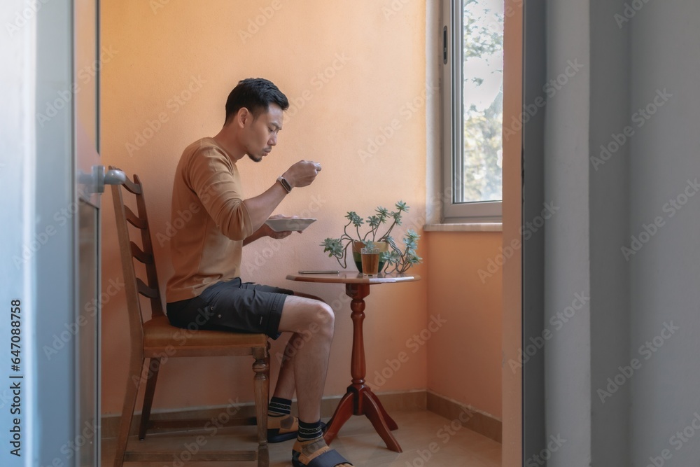 Man having breakfast soup on the terrace by the windows. Man having breakfast soup on the terrace by the windows.