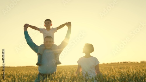 father mother child son happy family. happy family walking at sunset in wheat field. walk journey child boy on dad s shoulders. child surpergero dreams of flying. the dream of a little kid pilot