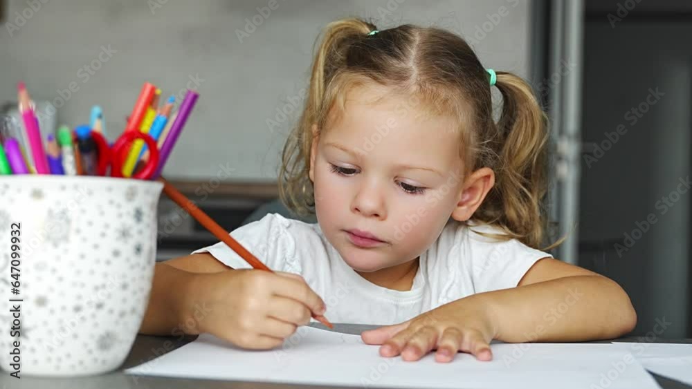 Little girl draws with colored pencils in home. 