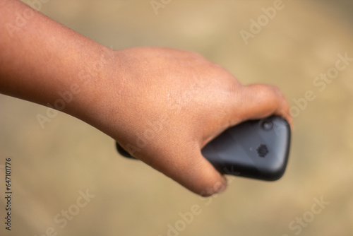 A human hand holds a small mobile phone and the background blur