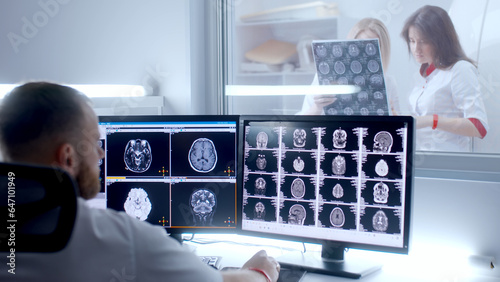 Medical hospital: neurologist use computer, analyze patient's MRI, diagnose brain. Health Clinic Lab: A professional doctor examines a functioning CT scan