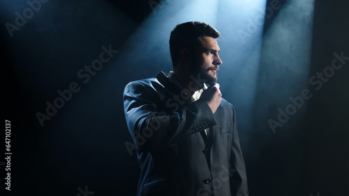 Attractive businessman posing stylishly against dark background © Vladislav