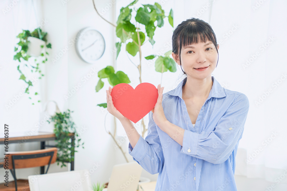 ハートマークをもつ自宅で仕事をする女性　立ちポーズ