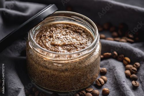 Organic oil scrub with sugar and coffee on the background of coffee beans on black cloth. Concept of natural cosmetics and skin care