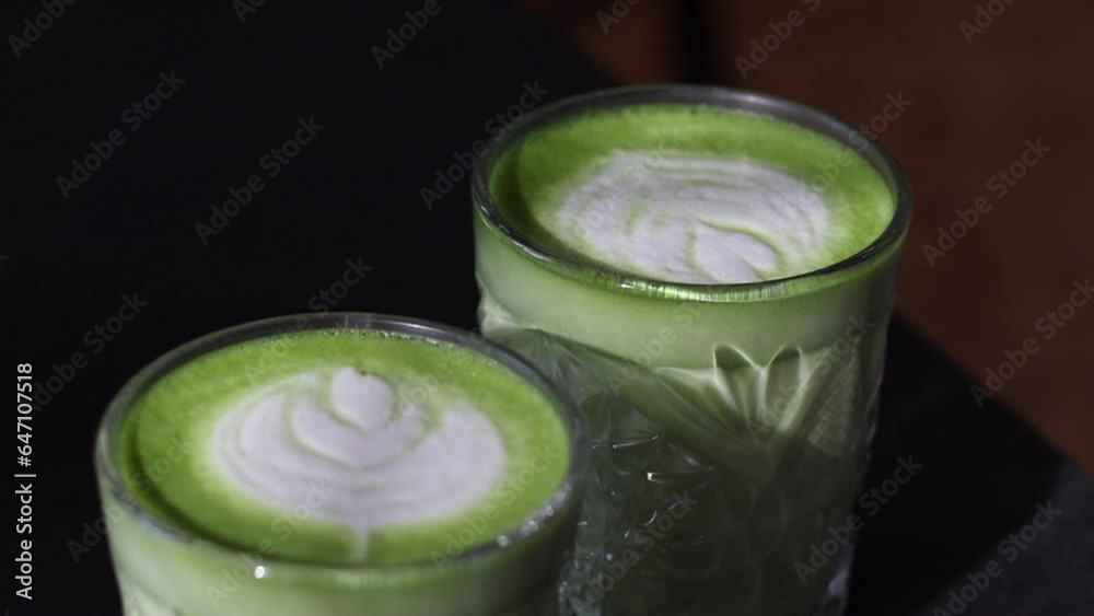 Green matcha with latte art on black background in cafe. Trendy tea in transparent cup close up. Top view Green matcha with latte art on black background in cafe. Trendy tea in transparent cup close up. Top view