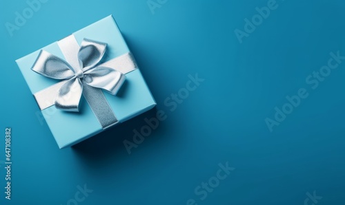 Gift box with satin ribbon and bow on blue background. Holiday gift with copy space. Birthday or Christmas present, flat lay, top view. Christmas giftbox concept. Generative AI