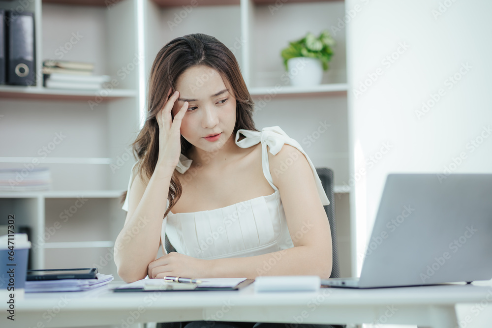 Asian woman stressed while working in the office Asian business woman who is tired from work feeling sick at work