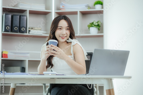 Young independent Asian woman working on laptop computer in modern office Perform accounting analysis, report real estate investment data. Financial concepts and tax system