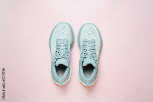 New light blue green female modern running shoe on pink background. Stylish monochrome shoes for active people that incorporate new health technology. Top view