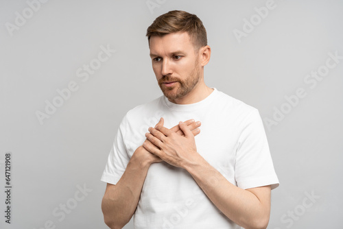 Fotografie Man has breathing problems, panic attack, suffocation holding hands on chest on gray background