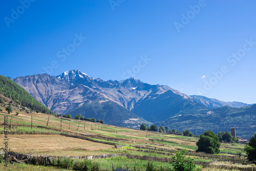 Gorgeous mountain scenery featuring the interplay of mountains and fields under a clear blue sky on a sunny summer day – a picturesque landscape. Georgian landscape