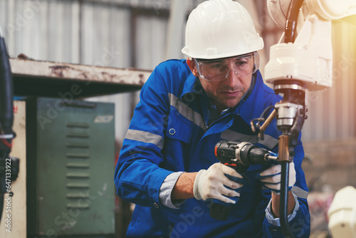 Male engineer worker repair automatic robotic arm in factory. Male technician worker inspecting quality automatic welding robot arm machine at production line