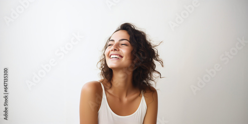 laughing woman with long dark hair in white top isolated on clean background