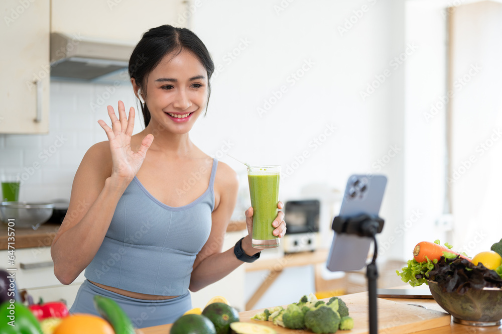A beautiful Asian female online nutrition coach is live streaming while making her morning smoothie. A beautiful Asian female online nutrition coach is live streaming while making her morning smoothie.