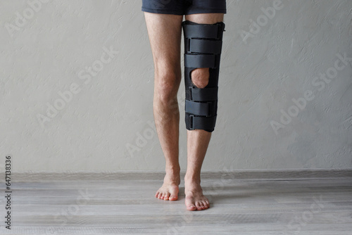 Patient standing with knee brace support after do posterior cruciate ligament surgery. Healthcare and medical concept.