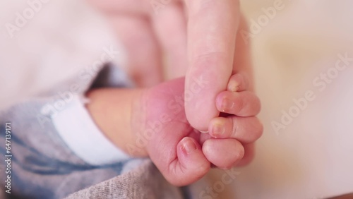mother holding tiny hand of newborn baby. happy family a kid dream concept. baby hand holds mom finger. newborn care lifestyle. sleeping baby hand holding mom hand