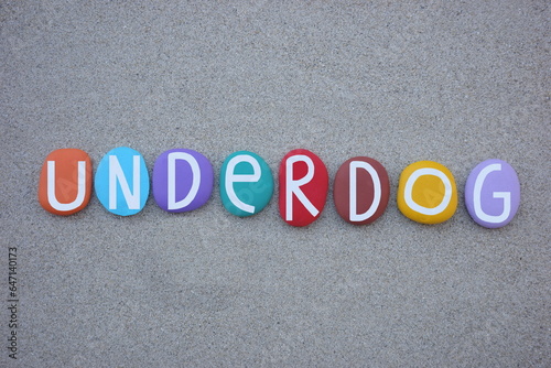 Underdog, person or group in a competition, usually in sports and creative works, who is largely expected to lose, creative text composed with multi colored stone letters over beach sand