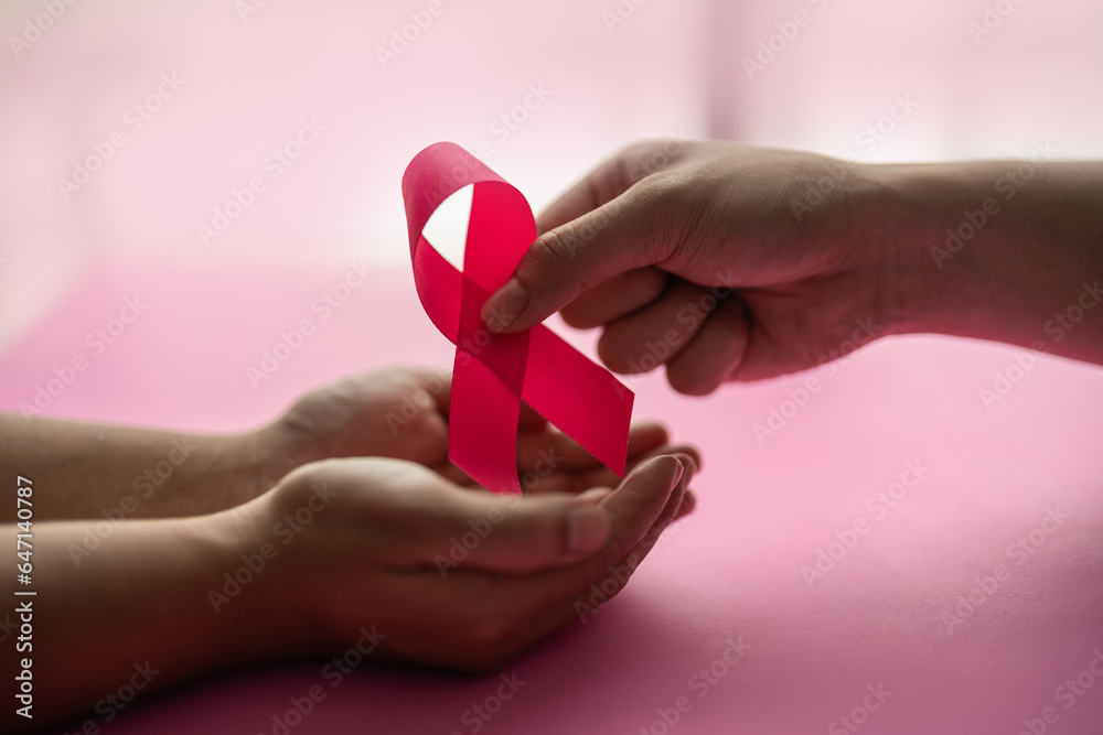 hands giving pink ribbon to sick person suffering from cancer, world cancer day, healthcare and medicine backdrop, suicide prevention, children health care. hands giving pink ribbon to sick person suffering from cancer, world cancer day, healthcare and medicine backdrop, suicide prevention, children health care.