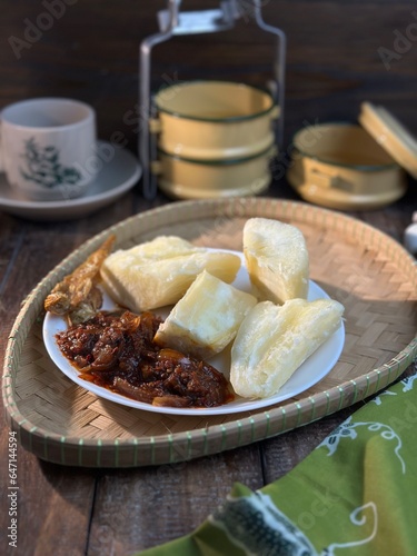 Ubi rebus or steam cassava is traditional malay dish. Serve with fried chili sambal over dark background. Selective focus.