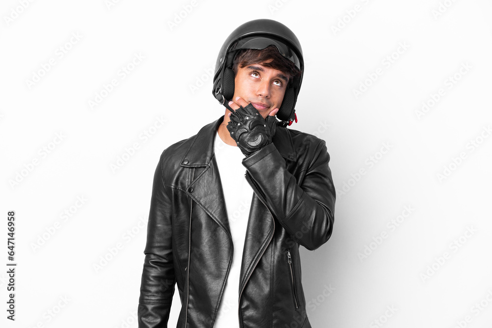 Young man with a motorcycle helmet isolated on white background having doubts Young man with a motorcycle helmet isolated on white background having doubts