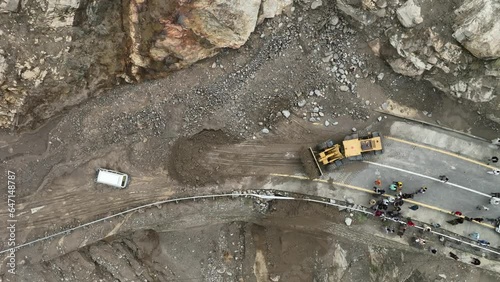 Drone tilting up movement aerial shot of yellow bulldozer clearing the landslide photo