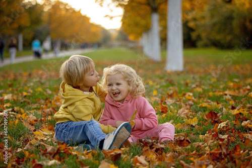 Cute blond toddler children boy and girl,walking in autumn park on sunset, enjoying the beautiful nature