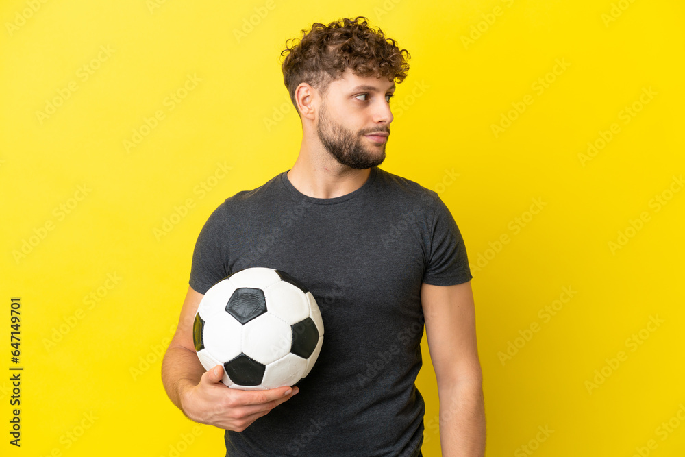 Handsome young football player man isolated on yellow background looking to the side