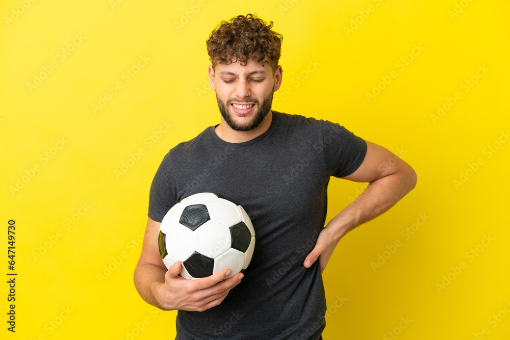 Handsome young football player man isolated on yellow background suffering from backache for having made an effort