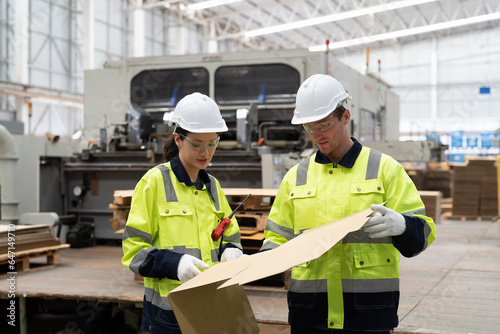 Male and female factory worker inspecting quality of cardboard in corrugated carton boxes warehouse storage. Group of factory worker checking cardboard corrugated carton boxes in factory