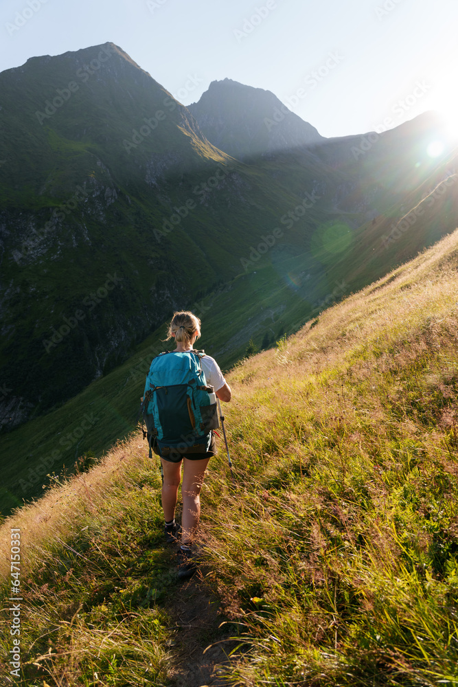 Girl with a backpack hiking in the evening light