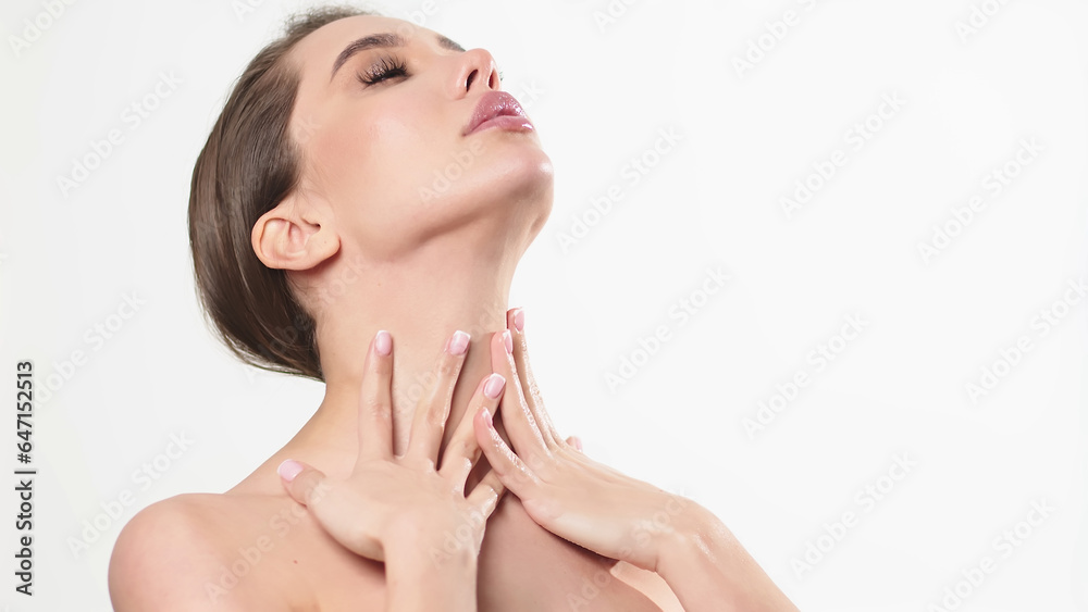 Portrait of an attractive dreamy tender girl doing a face and neck massage, isolated on a light background. Self care concept. Advertising of cosmetology and cleanliness. Portrait of an attractive dreamy tender girl doing a face and neck massage, isolated on a light background. Self care concept. Advertising of cosmetology and cleanliness.
