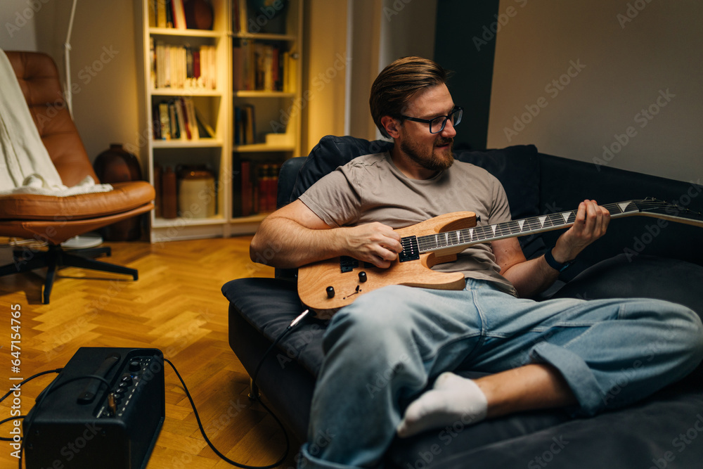 Caucasian man playing electric guitar at home.