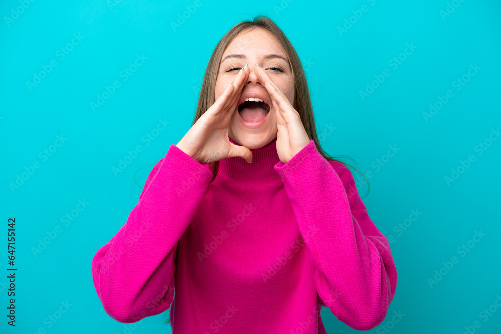 Young Lithuanian woman isolated on blue background shouting and announcing something Young Lithuanian woman isolated on blue background shouting and announcing something