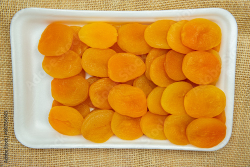 Dried apricot on rock plate in white foam top view
