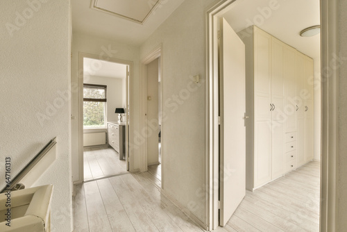 a hallway with white walls and wood flooring on the left side of the room, there is an open door leading to another