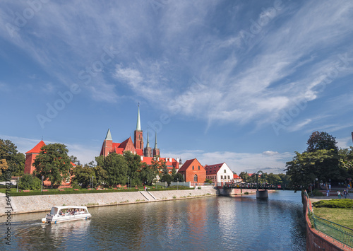 Obraz na płótnie Panoramic summer view of the beautiful green Tumski Island (Ostrów Tumski) in Wrocław, Poland (Dolny Śląsk). Boat on the Oder river in the foreground. w salonie