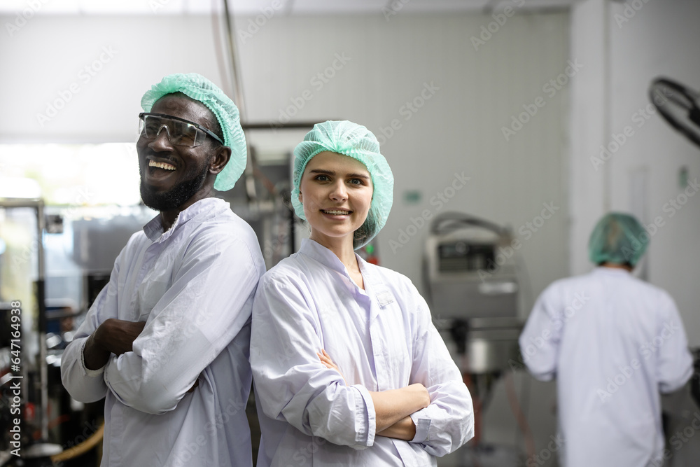 Portrait happy black worker laugh smiling together with woman friend standing arm crossed working in food and drink factory with hygiene
