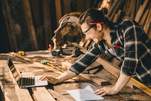 Carpenter man using modern technology computer laptop software aided sketch design new wooden furniture project