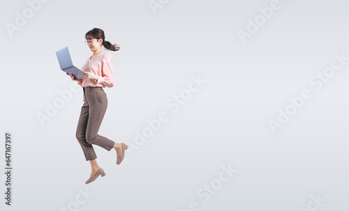 ノートパソコンを使いながらジャンプするミドル女性（切り抜き背景透過PNGも販売しております。作成者リンクから「PNG」で検索してください）