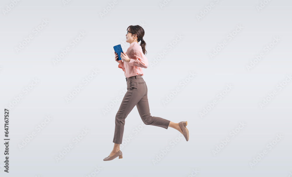 タブレットPCを使いながらジャンプするミドル女性（切り抜き背景透過PNGも販売しております。作成者リンクから「PNG」で検索してください）