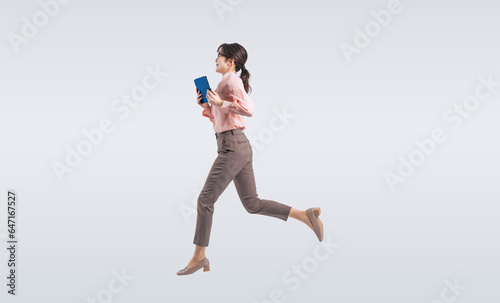 タブレットPCを使いながらジャンプするミドル女性（切り抜き背景透過PNGも販売しております。作成者リンクから「PNG」で検索してください）