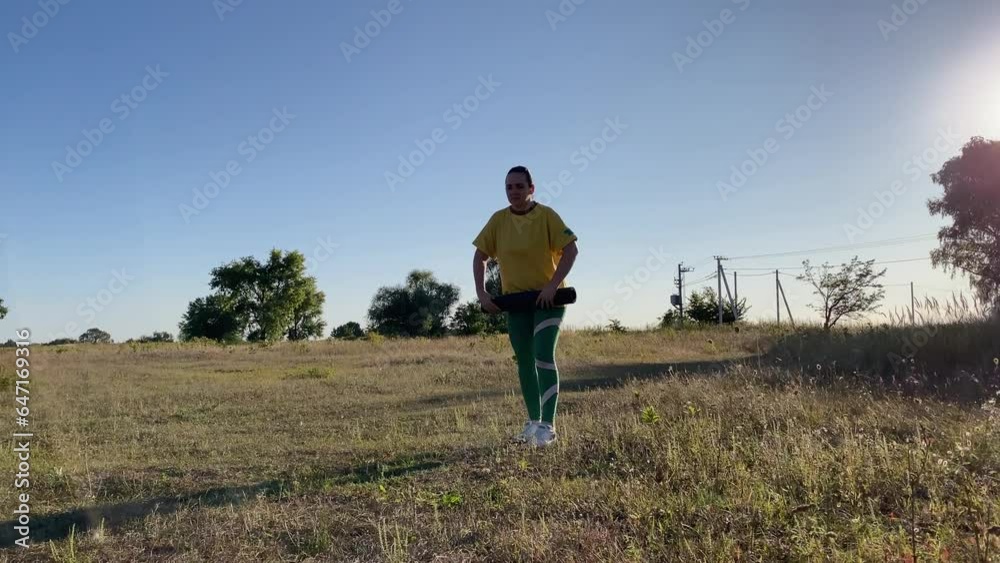 Determined young woman in vibrant sportswear prepares for evening workout routine in the open space of a serene rural scene. The clear blue sky, golden evening sunlight accent her positivity, strength Determined young woman in vibrant sportswear prepares for evening workout routine in the open space of a serene rural scene. The clear blue sky, golden evening sunlight accent her positivity, strength