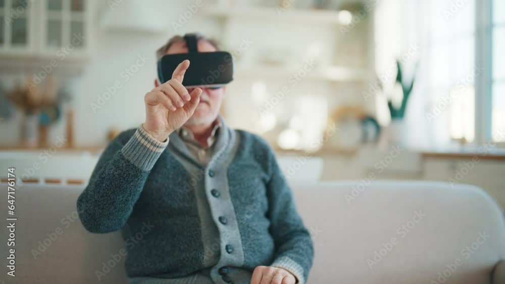 Happy senior man in virtual goggles plays video game touches objects in air in cyberspace. Looks at virtual world in VR helmet. Modern methods of medical restoring motor activity after heart attacks. Happy senior man in virtual goggles plays video game touches objects in air in cyberspace. Looks at virtual world in VR helmet. Modern methods of medical restoring motor activity after heart attacks.