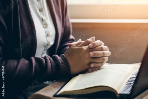 Women's hands are folded in prayer on a Holy Bible over a laptop in church concept for faith, religion, love, and forgiveness. Holy Bible study reading together in Sunday school.Online, Generative AI photo