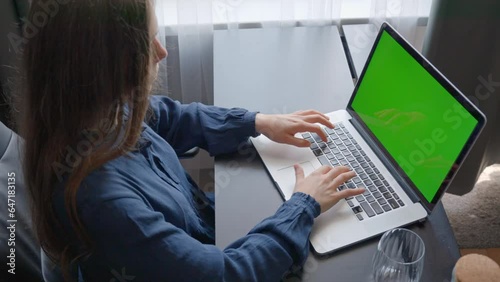 Overhead close up of woman in office typing on laptop with green screen photo